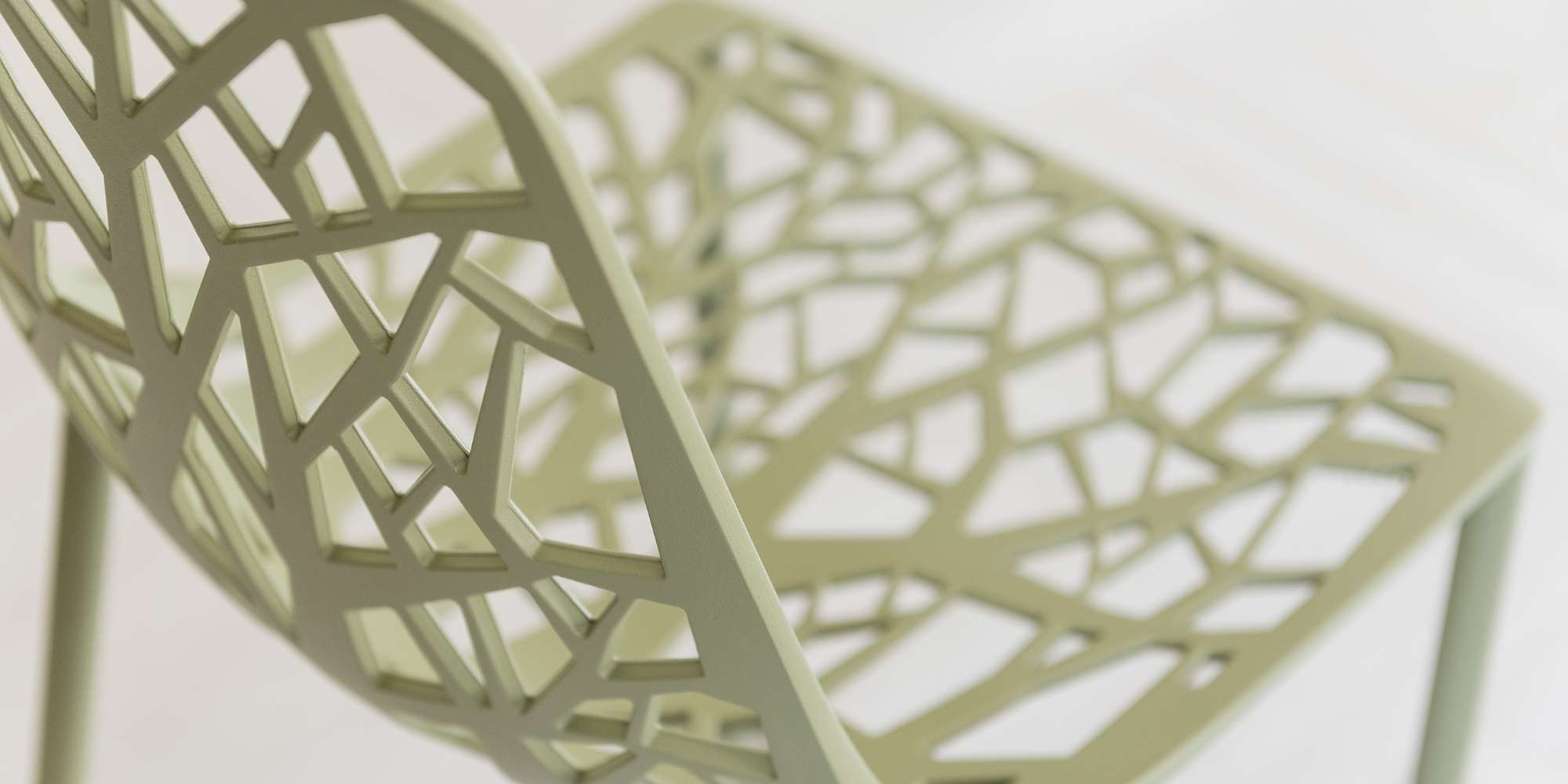 A close-up photograph shows an open, rhomboidal pattern that makes up the metal framing of a decorative side chair.